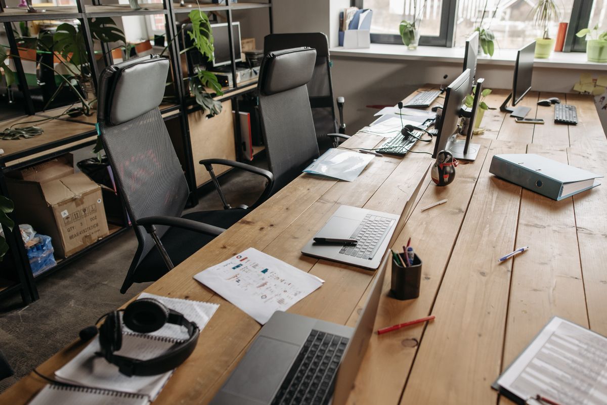 Mesa compartida con portátiles, monitores y material de oficina